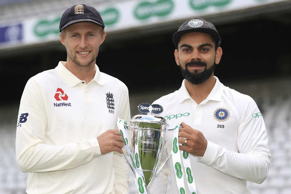 England and India cricketers in white Test uniforms holding a trophy.