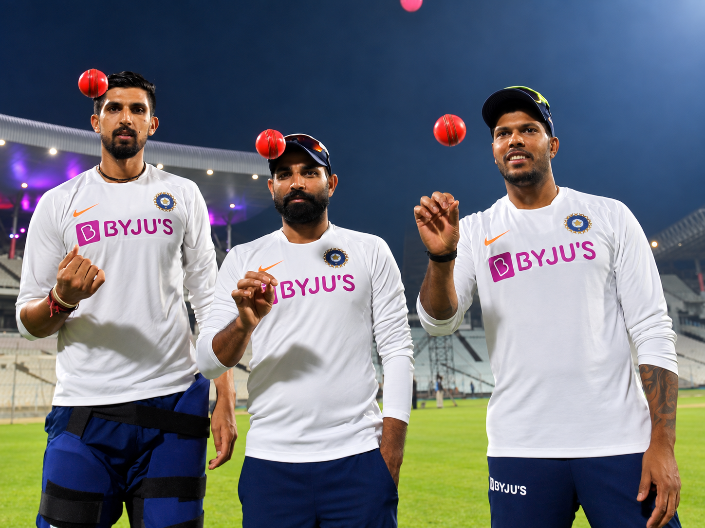 Three India cricketers tossing cricket balls during training under stadium lights