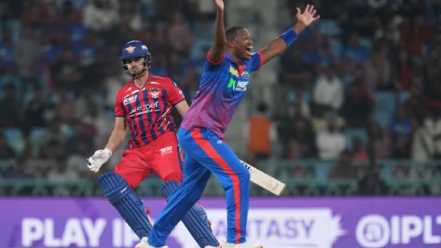 A fast bowler appeals with both arms raised during an IPL match.